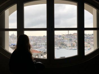 Rear view of woman looking through window