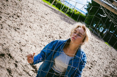 Young woman standing by net