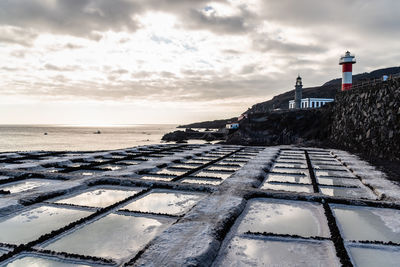 Salinas of fuencaliente, la palma, canary islands. salt extraction besides the lighthouse at sunset