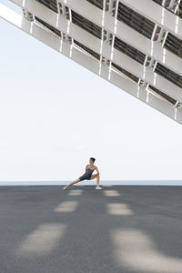 Female sportsperson stretching under built structure