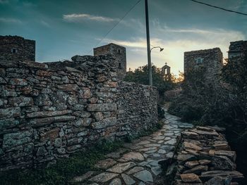 Stack of stone wall by building against sky