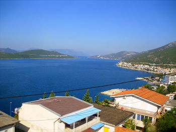 High angle view of townscape by sea against blue sky