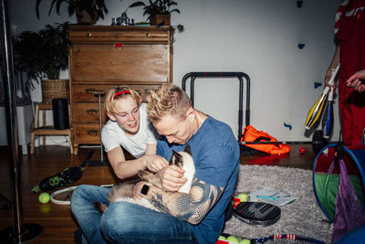 Father and son stroking cat in living room