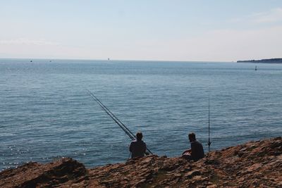 People fishing in sea against sky