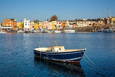 Sailboats moored on harbor by buildings in city against clear sky