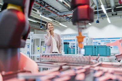 Businesswoman on cell phone in a modern factory hall
