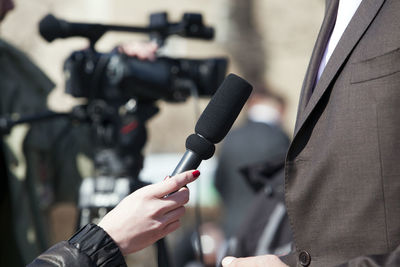 Cropped image of news reporter holding microphone while taking interview