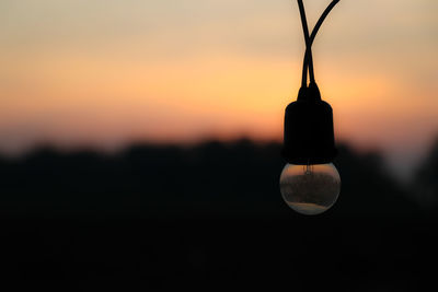 Close-up of light bulb against sky during sunset