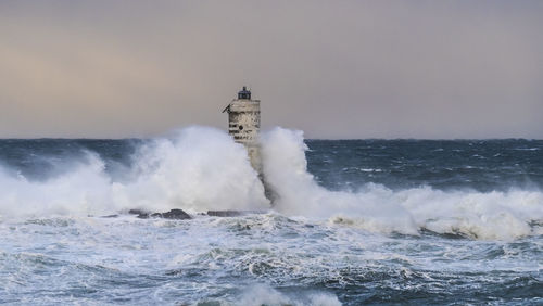 Waves splashing on shore against clear sky