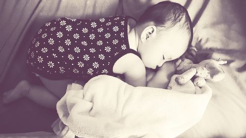 Close-up of baby sleeping on bed at home