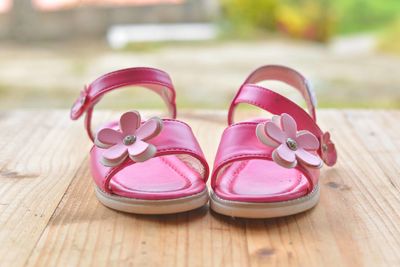 Close-up of pink sandals on wooden table