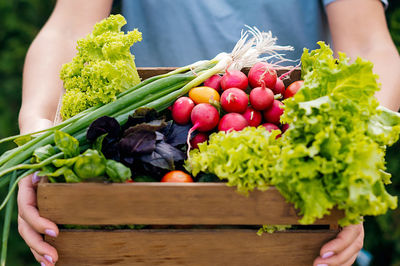 Midsection of woman picking vegetables on table