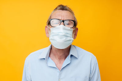 Portrait of senior man wearing mask against yellow background