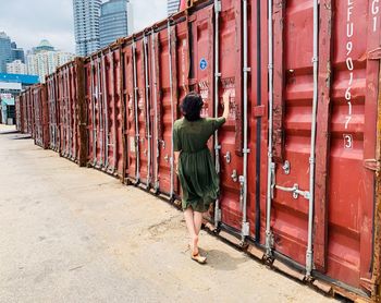 Rear view of woman standing by container