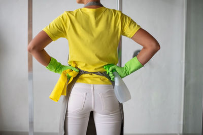 Rear view of man standing against yellow wall