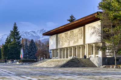 Building by trees in city against sky