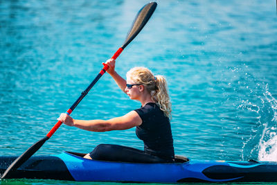 Side view of young woman kayaking on lake
