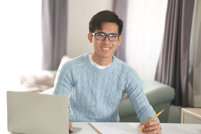 Portrait of smiling young man using laptop on table