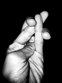 Close-up of father holding hand against black background