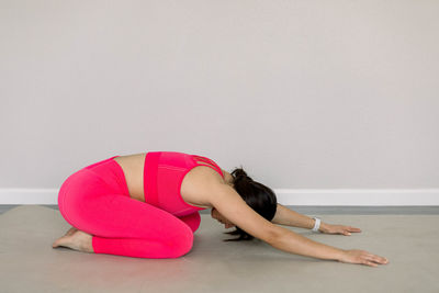 Side view of woman doing yoga at home