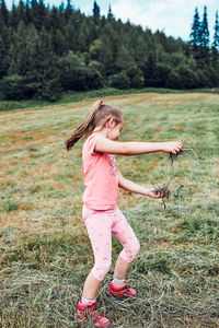 Little girl playing with grass enjoying summer day. happy child playing in the field during vacation