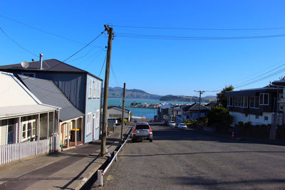 Cars on road by buildings against clear sky