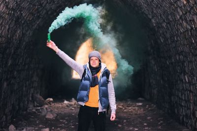 Portrait of young man holding flare in cave