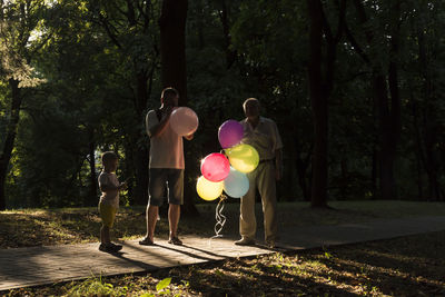 Grandfather, dad and son, the whole family spend time in the park and inflate balloons.