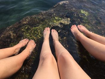 Low section of women dangling legs on rock