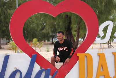 Full length of man making heart shape sign