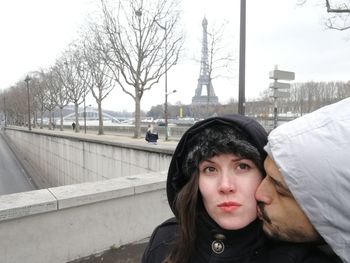 Man kissing woman while standing in city during winter