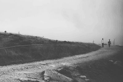 People walking on field against sky