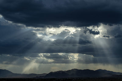 Low angle view of storm clouds over silhouette mountain