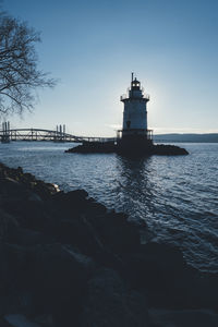 Lighthouse by sea against sky