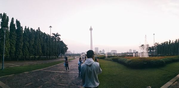 Rear view of man standing in city against clear sky