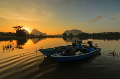 Boats moored at lake during sunset