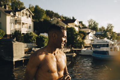 Shirtless wet man looking at lake in summer