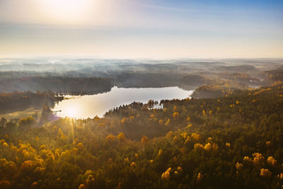 Scenic view of lake in forest against sky during sunset