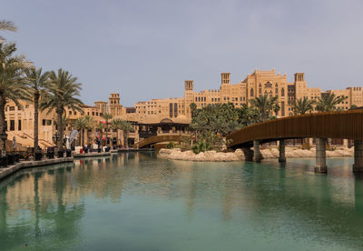 Bridge over river by buildings in city against sky