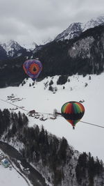 Hot air balloon flying over snowcapped mountains against sky