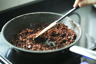 Close-up of person preparing food in cooking pan at home