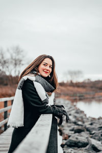 Young woman standing in snow against sky during winter