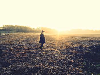 Woman walking on field during sunset