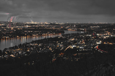 High angle view of illuminated city by river against sky