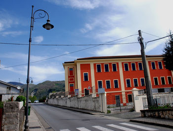 Road by buildings in city against sky