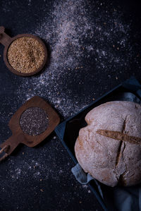 Exposed bread on a dark background, with its ingredients of seeds and flax.