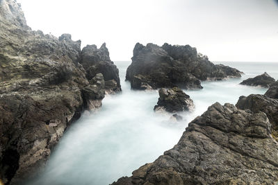 Scenic view of rocks in sea against sky