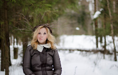 Portrait of young woman standing on tree trunk
