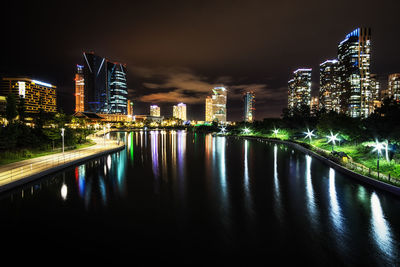 Illuminated buildings by river at night