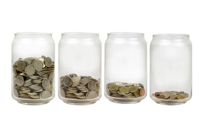 Close-up of coins in jar against white background